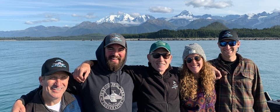 Three people standing in front of a body of water.