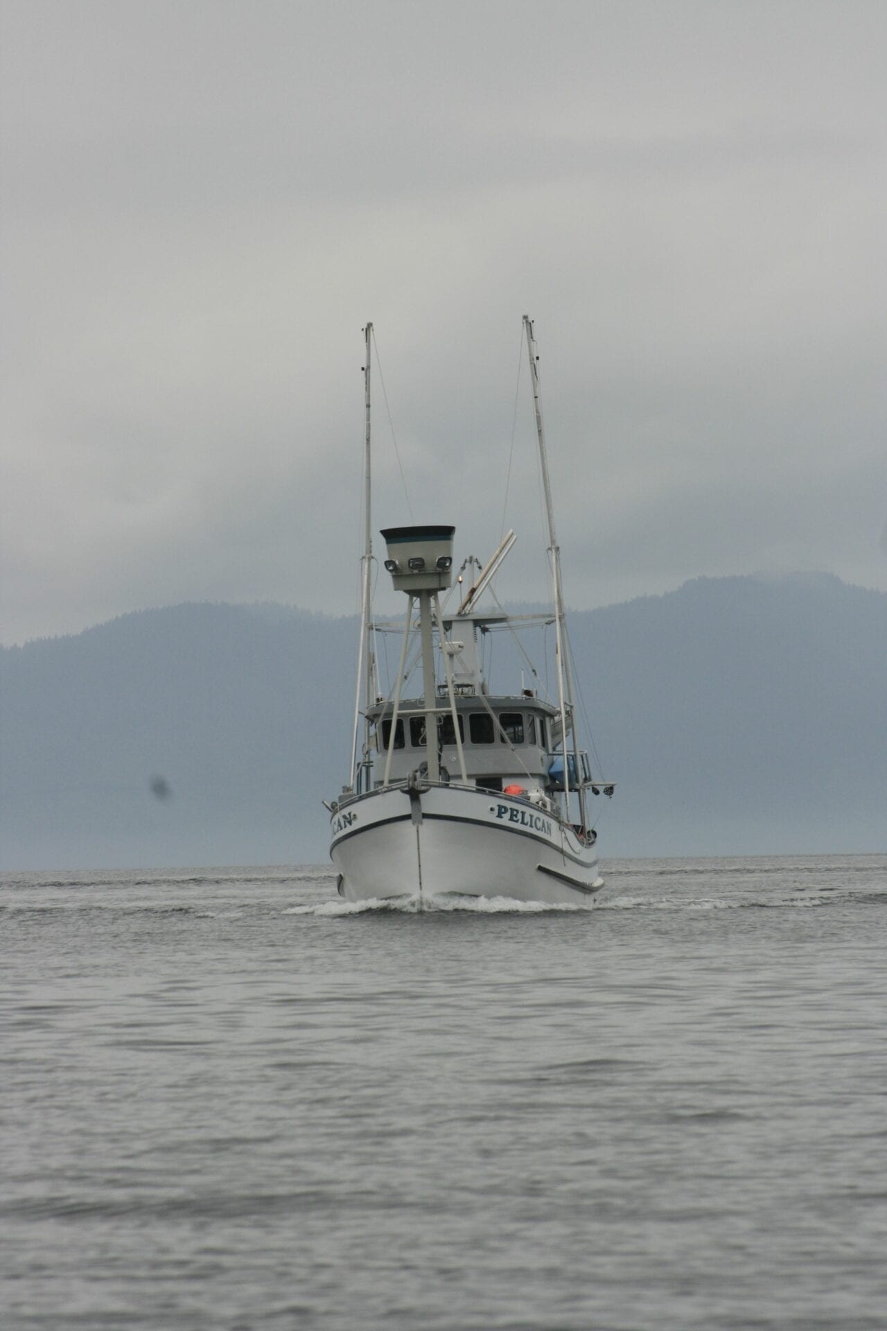 A boat is sailing in the ocean on a cloudy day.