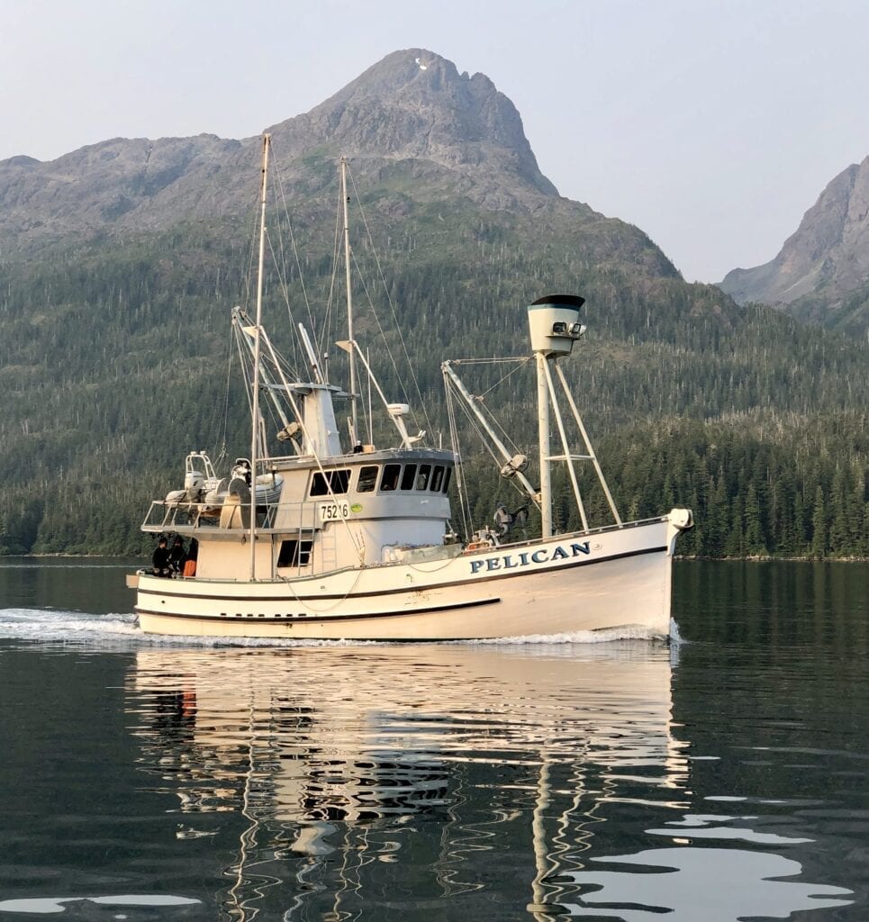 A boat is sailing on the water near some mountains.