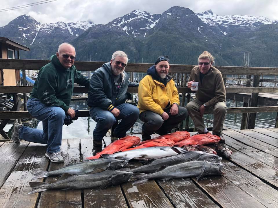 A group of men sitting on top of a dock.