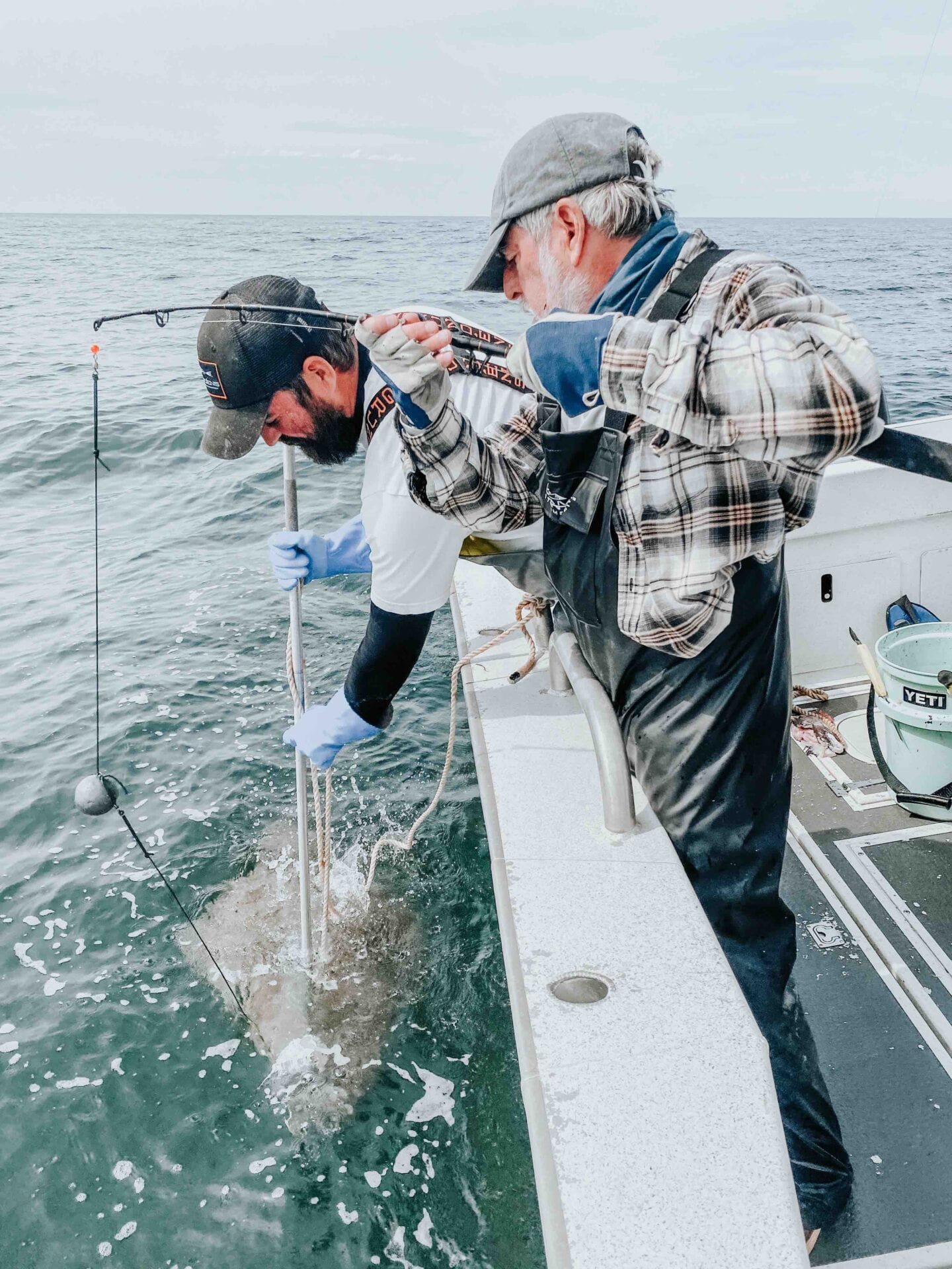 Two men on a boat fishing for fish.