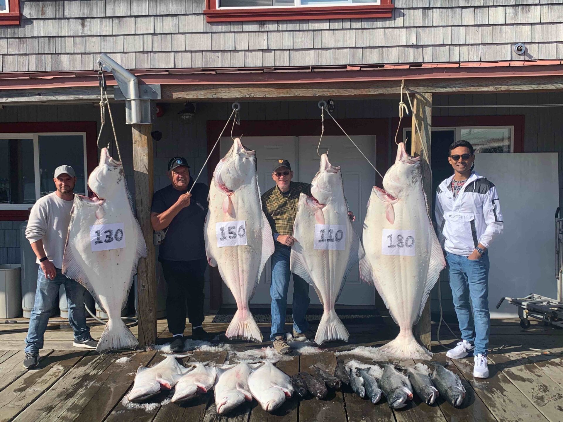 A group of people standing next to large fish.