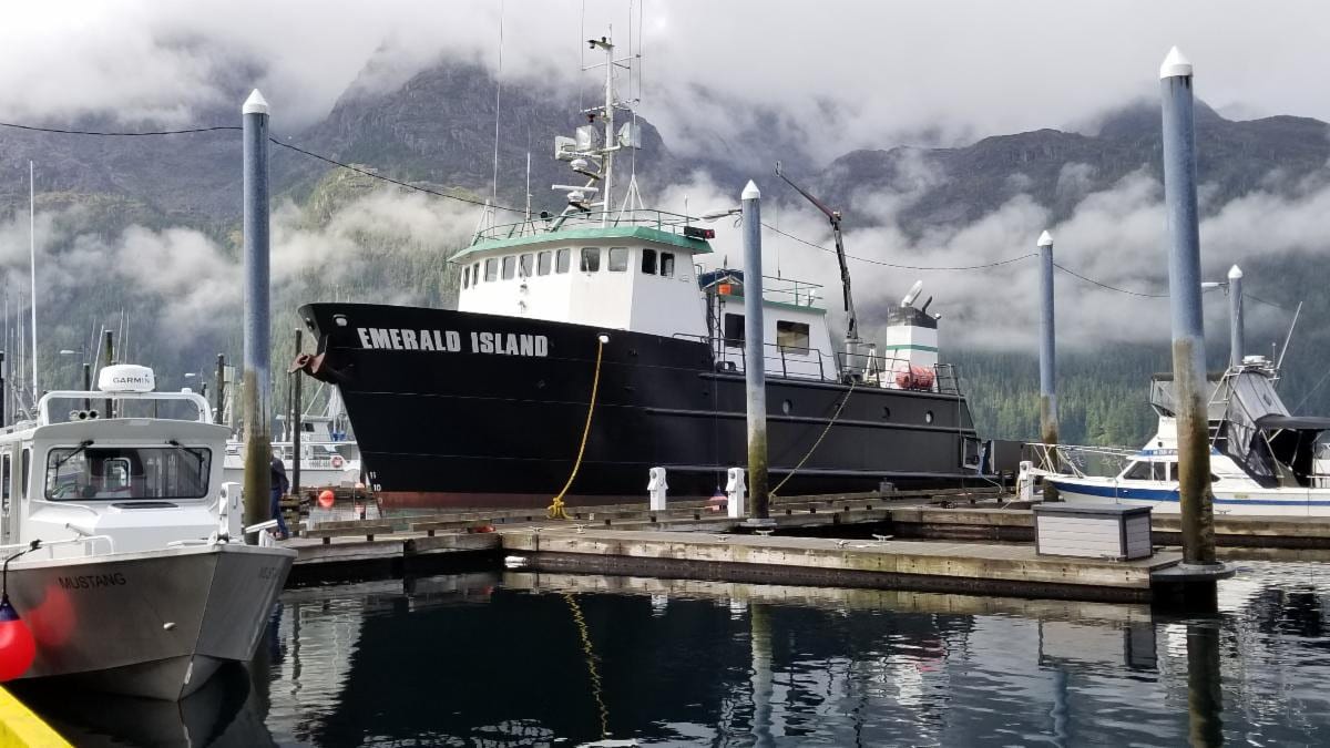 A boat docked at the dock in front of mountains.