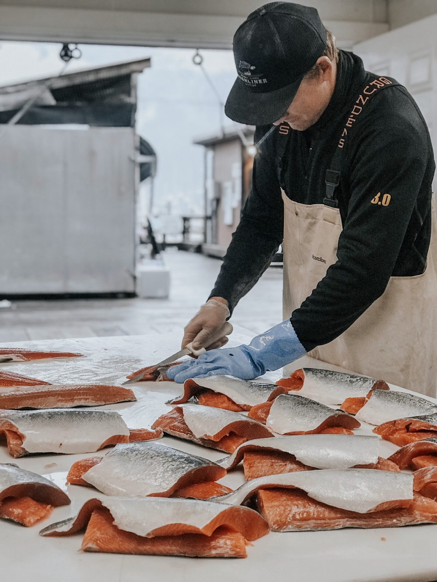 0DCDDF3A-8588-4D73-BC76-1FE745357089 A person cutting fish on top of a table.