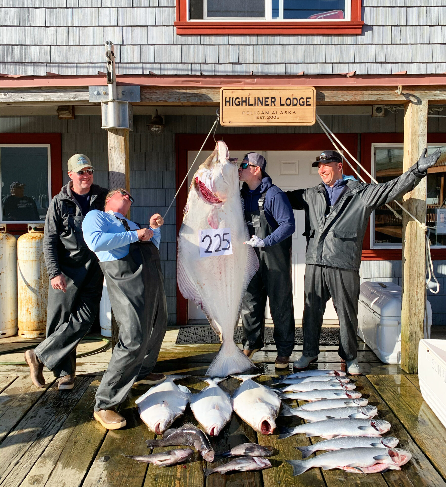 A group of men standing next to fish on the dock.