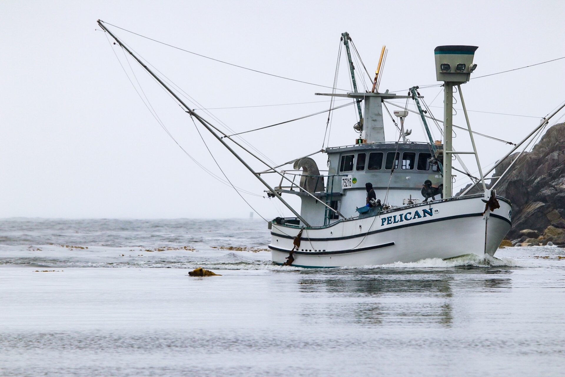 A boat is in the water near some rocks.